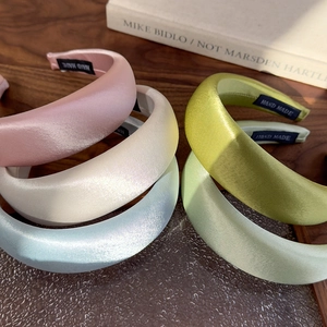 Macro shot of 4cm wide satin headbands in pastel colors showing the silk texture and handmade label