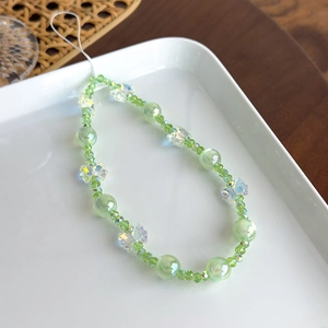 Détail de la dragonne de téléphone en perles avec papillon aurore et perles vertes