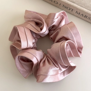 Detail of elegant champagne satin scrunchie with French style ruffled floral texture