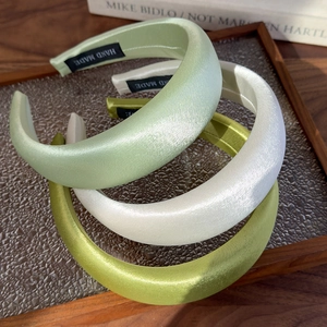 Detail view of handmade satin padded headbands in mint, cream and olive green