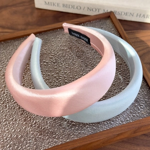 Close-up of pink and blue satin padded headbands with a handmade fabric label on the inner side