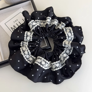 Detailed view of large black satin scrunchie with white polka dots and lace trim