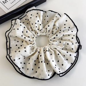 Detail of oversized white chiffon scrunchie with black polka dots and contrast edging