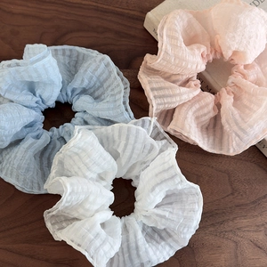 Trois chouchous en seersucker à carreaux bleu, rose et blanc sur table en bois