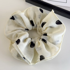 Détail du chouchou élégant en mousseline crème avec de grands pois noirs et texture quadrillée