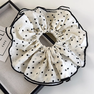 Macro shot of oversized white scrunchie with black polka dots and stitched edges