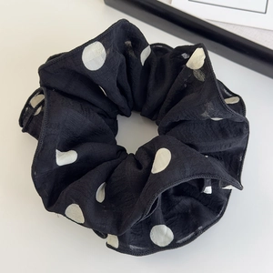 Gros plan du chouchou élégant en mousseline à pois noirs et blancs avec texture à couches