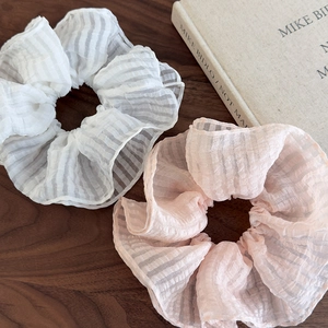 Détail de chouchous en seersucker rose et blanc avec texture rayée sur table en bois