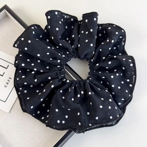 Close-up detail of oversized black and white polka dot scrunchie with soft pleated texture