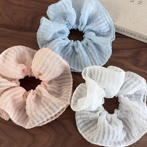 Vue détaillée de trois chouchous en seersucker à carreaux bleus, roses et blancs sur bois