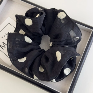 Vue détaillée du chouchou élégant en mousseline noire à pois blancs et texture plissée