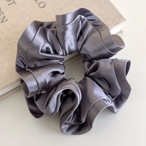 Close-up of elegant silver-grey satin hair scrunchie with smooth pearlescent texture