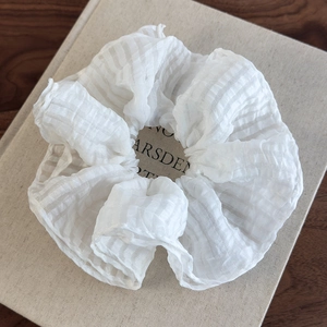 Détail d'un chouchou en seersucker blanc avec texture plissée sur un livre ancien