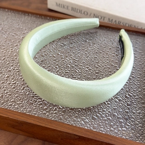 Detail showing high-gloss light green satin fabric texture on thick padded headband