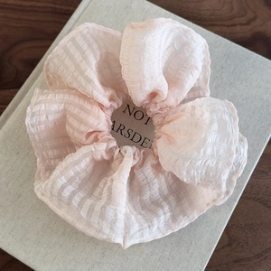Détail de chouchou en seersucker rose pastel avec volants superposés et tissu texturé doux