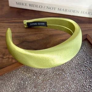 Detail of the high crown grass green satin headband with a Hand Made label