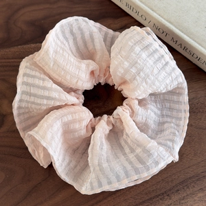 Vue détaillée de la texture du chouchou rose en seersucker à carreaux sur bois