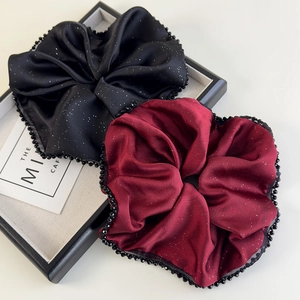 Détail des chouchous en satin noir et bordeaux avec des reflets argentés et bordure de perles