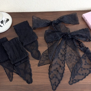 Elegant black lace hair ribbon with floral embroidery and French style bow on wood desk