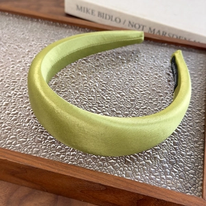 Detail view of avocado green satin padded headband with non-slip lining on wood tray