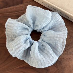 Détail du chouchou en seersucker bleu clair avec fil pailleté argenté et texture plissée