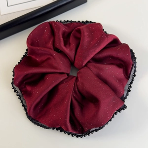 Gros plan détaillé du chouchou en satin bordeaux avec paillettes et bordure de perles
