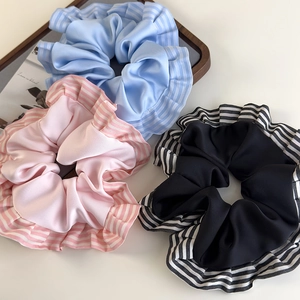Détail de chouchous en satin avec bords volantés rayés en bleu, rose et noir