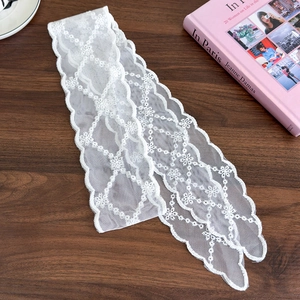 Close-up of white floral lace ribbon with delicate embroidery on a wooden surface