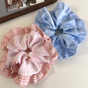 Détail de chouchous en satin rose et bleu avec bords à volants rayés en présentation