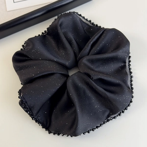 Vue détaillée du chouchou en satin noir avec paillettes scintillantes et perles