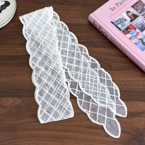 Macro detail of white lace ribbon with wavy floral edges and mesh texture on wood
