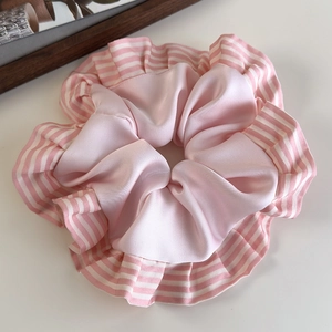 Vue détaillée du chouchou en satin rose avec bord plissé rayé et texture soyeuse
