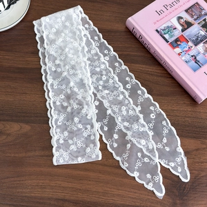 Detail of white lace hair ribbon with floral embroidery and delicate wavy edges on wood