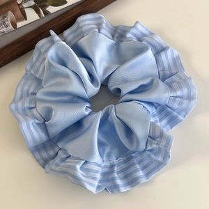 Détail macro d'un chouchou en satin bleu clair avec des bords plissés à rayures