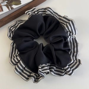 Détail d'un chouchou large avec centre en satin noir et bords à rayures plissés élégants