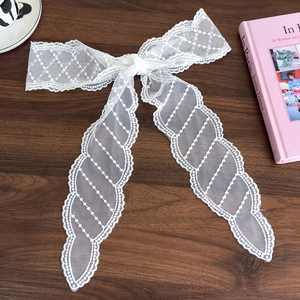 Detail of white lace headband showing intricate mesh texture and elegant bow design