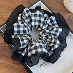 Detailed macro of black and white plaid scrunchie with lace trim in a display tray