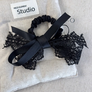 Chouchou élégant avec nœud en dentelle noire vintage et texture soie sur lin beige