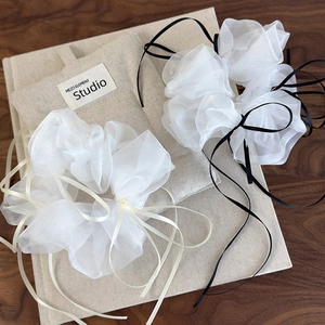 Elegant organza scrunchies with long ribbons on wooden surface for French ballet core hairstyles
