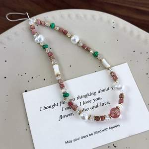 Detalle de la correa para móvil con cuentas de colores y piedras en plato de cerámica