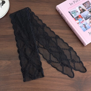 Close-up of black lace headband with floral embroidery and wavy edges on wooden table