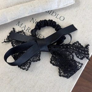 Détail de l'élastique à cheveux en dentelle noire et ruban de satin sur fond de livre décoratif