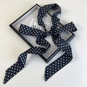 Gros plan détaillé d'un long foulard en soie à pois noirs noué en un élégant nœud papillon