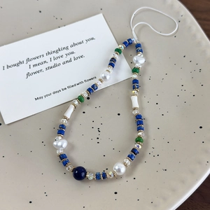Detalle de la correa de móvil con perlas barrocas, piedras minerales azules y cristales