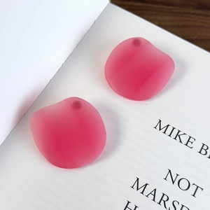 Lichtdurchlässige rosenrote Shrimp-Chip-Ohrringe auf einem weißen minimalistischen Buch