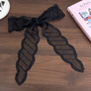 Close-up of vintage black lace ribbon hair tie with embroidery on a rustic wooden background