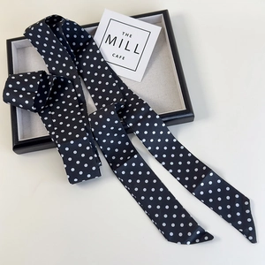 Vue détaillée d'une écharpe en satin à pois noirs et blancs sur un plateau