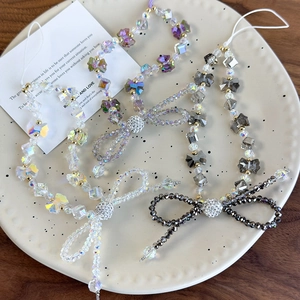 Close-up of handmade crystal beaded phone lanyards with bow charms in various colors