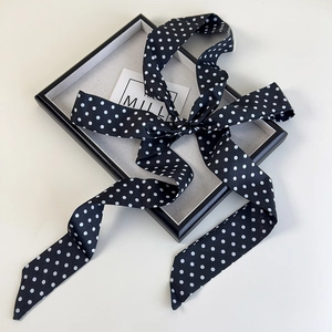Gros plan d'un foulard en soie à pois noirs et blancs sur un plateau minimaliste