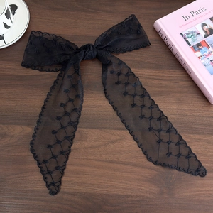 Close-up of black lace bow hairband with delicate floral patterns and long flowing ribbons